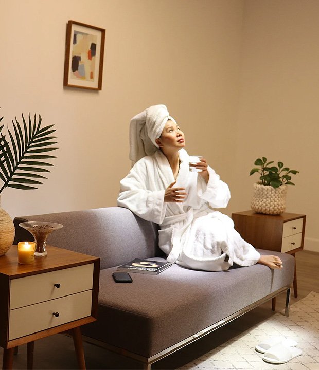 A young woman enjoying a cup of tea while soaking up the afternoon sun glow from Innerscene’s Virtual Sun light fixture.